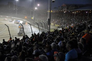 A giant crowd watches as the trucks line up for a late-race restart in the 1-800-Car-Cash Mud Summer Classic