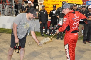 Track owner Tony Stewart helps race winner Christopher Bell scoop up a souvenir jar of Eldora clay following the event.